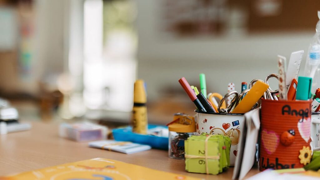 Nahaufnahme eines Schreibtischs mit mehreren Stiften, Markern auf einer Holzoberfläche.